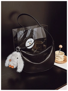 Close-up of black hobo shoulder bag with silver zipper and grey plush rabbit pendant