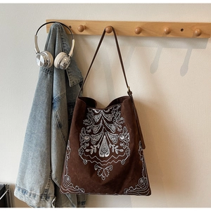 Detail der weißen Blumenstickerei auf einer braunen Wildleder-Tragetasche im Vintage-Stil