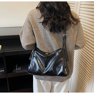 Detail of black glossy leather tote bag with adjustable slim shoulder strap and soft texture