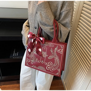 Detailed embroidery of Chinese traditional patterns and red ribbon on bridal handbag