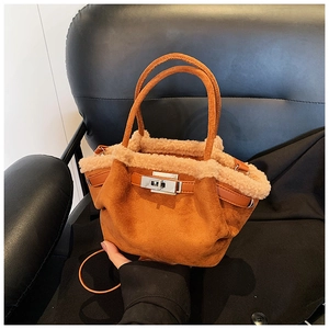 Detail of a burnt orange suede bucket bag with faux fur trim and gold twist-lock closure