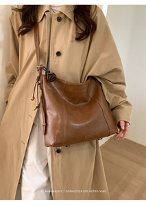 Détail d'un sac à bandoulière en cuir marron avec pompon vintage et logo en métal