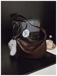Detail of dark brown leather hobo bag with silver zipper and cute plush goose pendant