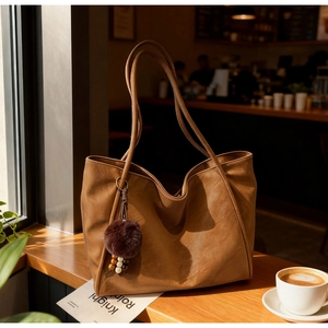 Close-up of brown faux leather tote bag texture with decorative wooden bead pompom detail