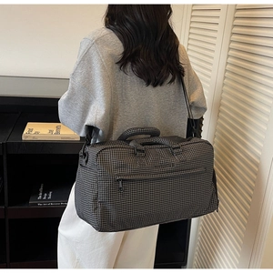 Detail der karierten Reisetasche mit verstärkten Griffen und verstellbarem Schultergurt