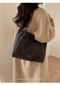 Close-up of black matte leather tote bag with silver rings and brand text on shoulder
