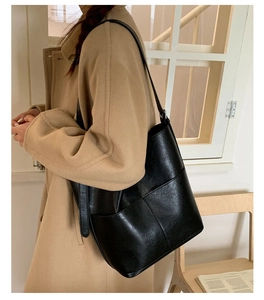 Détail d'un sac seau en cuir noir avec coutures croisées et bandoulière réglable