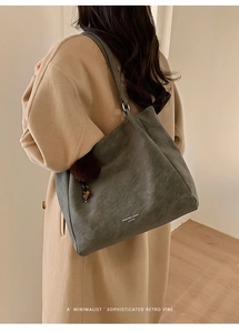 Large olive green suede tote bag with fur charm shown on shoulder with autumn coat