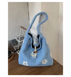 Detail of blue plush tote bag with daisy embroidery, drawstring and horn button closure