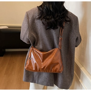 Close-up of caramel faux leather crossbody bag with tassel detail and metal ring