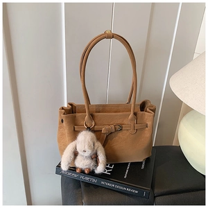 Brown faux leather tote bag detail with decorative strap and a cute plush rabbit charm