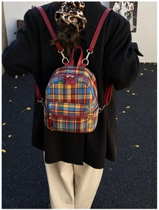 Detail view of colorful plaid tweed backpack with red leather straps on a female model