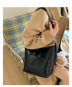 Détail d'un sac seau noir porté sur un manteau chameau pour un look d'automne élégant