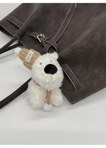 Dettaglio di un ciondolo a cane di peluche bianco con cappello su borsa Boston in pelle