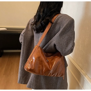 Detailed back view of a brown vintage tote bag in glossy leather on a model's shoulder