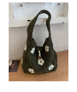 Detail of green knitted tote bag featuring white floral embroidery and wooden horn button