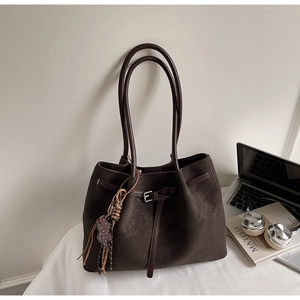 Close-up of a vintage dark brown tote bag with bear charm and colorful tassel accents
