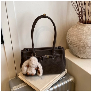 Detail of dark brown tote bag with white stitching and cute plush rabbit keychain