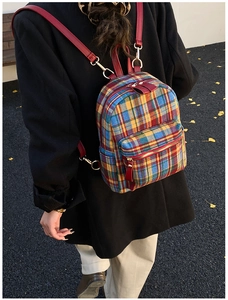 Detailed back view of a colorful plaid tweed backpack with red leather straps in autumn