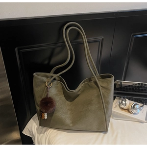 Detail of olive green tote bag with matte texture and decorative faux fur charm