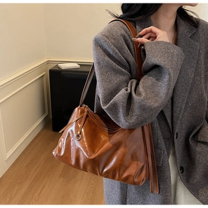 Detail of vintage brown glossy leather tote showing natural texture and brand engraving