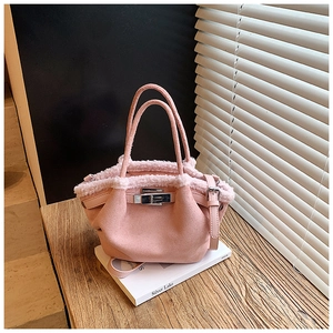 Detailed close-up of pink suede bucket bag with faux shearling trim and silver metal lock