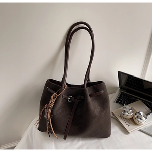 Detail of dark brown faux suede tote bag with long tassel and belt buckle strap