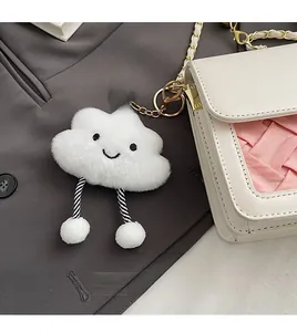 Detailed view of white plush cloud keychain with a smiling face on a leather bag