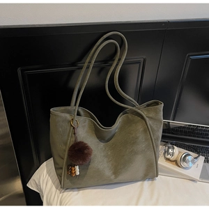 Macro detail of olive green tote bag with plush charm and wooden bead accessory