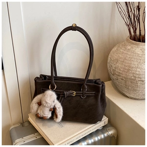 Detail of dark brown suede tote bag with white stitching and cute plush bunny charm