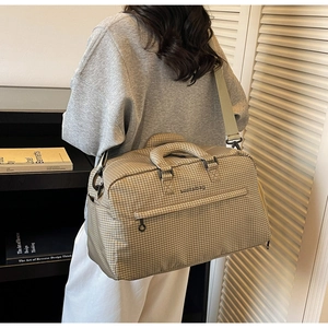 Detail der karierten Reisetasche mit verstellbarem Gurt in gemütlicher Wohnumgebung