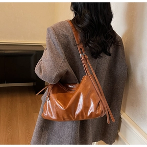 Detailed back view of a large vintage caramel hobo tote bag worn by a model in a minimalist room