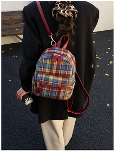 Close-up of vintage plaid tweed backpack with red leather straps on model in autumn park