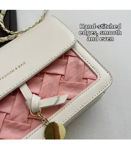 Detail showing hand-stitched pink and white woven texture with gold chain strap