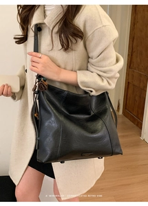 Détail d'un sac cabas noir en cuir synthétique montrant la texture et la bandoulière