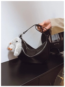 Detail of black glossy crescent moon bag with silver zipper and plush rabbit charm
