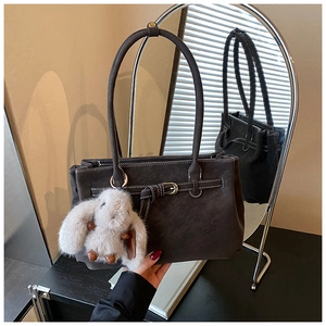 Detail of dark grey tote bag with matte texture and cute white bunny charm