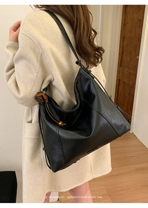 Sac Hobo noir chic avec texture litchi et glands en perles de bois sur un mannequin