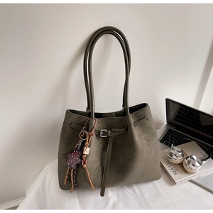 Detail of dark green matte tote bag with decorative charms and premium leather texture