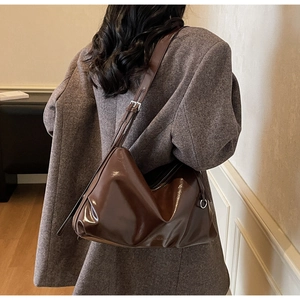 Detail of a large brown hobo bag with a glossy finish and an adjustable shoulder strap