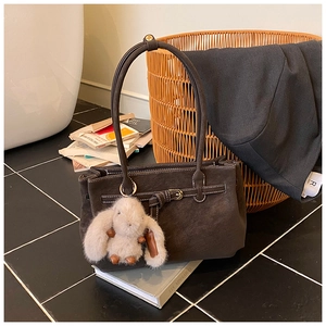 Detail of dark coffee tote bag with white stitching and plush rabbit charm on books