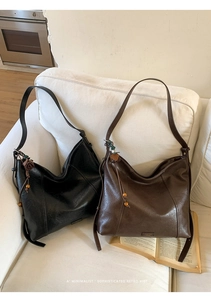 Détail de sacs hobo en cuir noir et marron avec pendentifs tressés sur un canapé