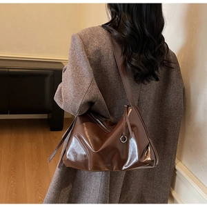 Close-up of high-gloss dark brown leather tote bag with metallic ring and zipper detail