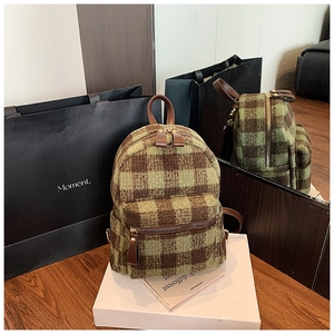 Detail of green and brown plaid wool backpack with leather handle and metal zippers