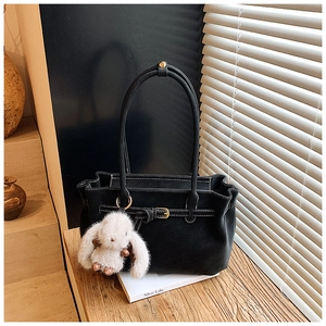 Detail of black suede tote bag with contrast stitching and plush rabbit charm on side