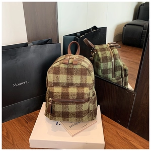 Detail of green checkerboard plaid wool backpack with leather zipper pulls and handles