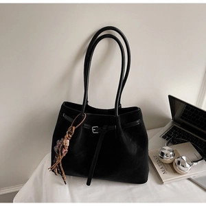 Detail of black suede tote bag with silver buckle and decorative beaded charm