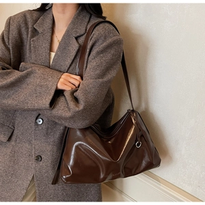 Model wearing dark brown glossy leather tote bag with SOLAR&MISS embossed lettering