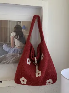 Red knit tote bag with white flower embroidery and toggle closure in home setting
