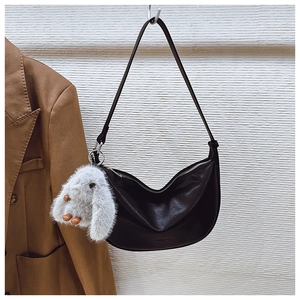 Detail of black leather crescent bag with silver zipper and cute bunny charm pendant